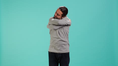 retrato de un hombre de pie en el estudio, abrazándose a sí mismo, haciendo amor propio