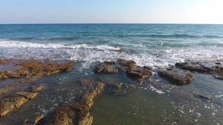 Vista aerea di onde delicate che si infrangono su una costa rocciosa.