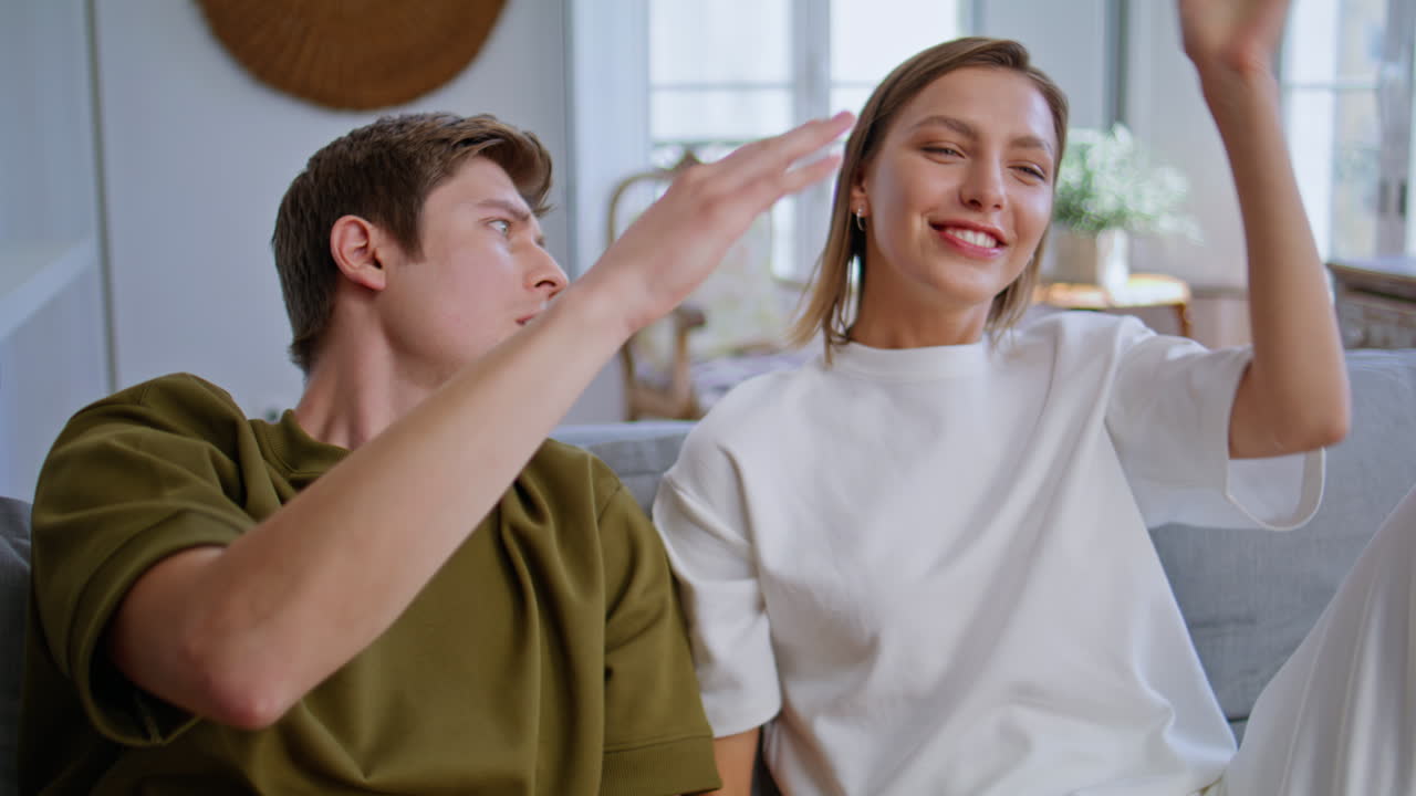 Young couple competing online sitting sofa at home closeup. Woman winning game