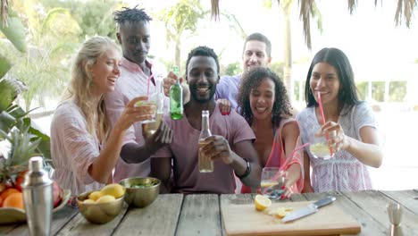 Portrait-of-happy-diverse-group-of-friends-talking-and-drinking-drinks-at-beach-bar