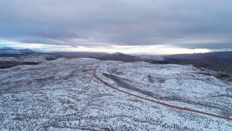 Aerial-drone-shot-flying-over-the-snow-covered-desert-looking-over-a-cliff