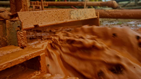 orange clay flowing under pressure during the drilling process. oil or gas production on the special site. close up.