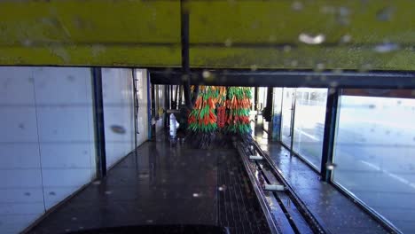 automatic car wash as seen from back of vehicle moving through machine tunnel and dryer