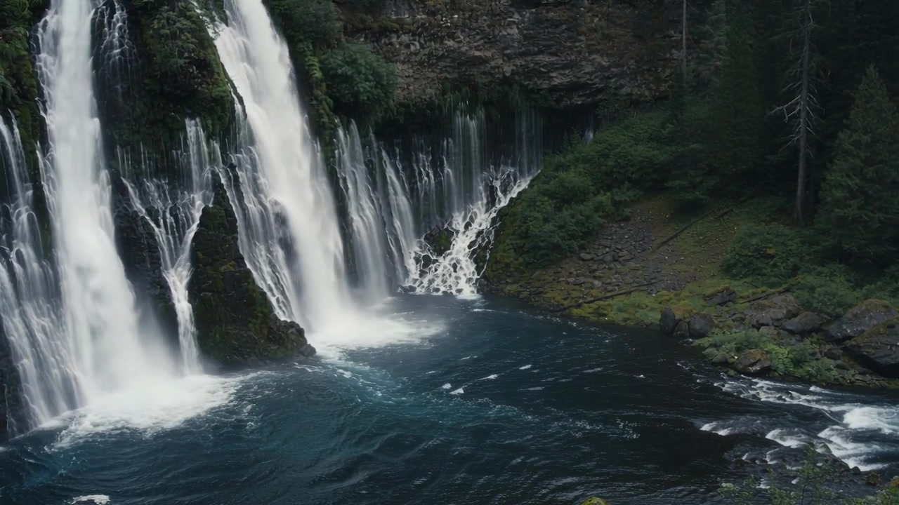 Flowing river feeding multiple falls in gorge, cascading down moss cliff into pool feeding outflow