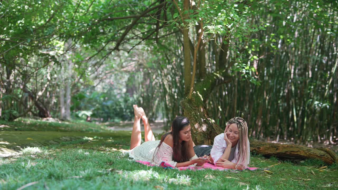 Two women relaxing on a picnic blanket in a bamboo forest