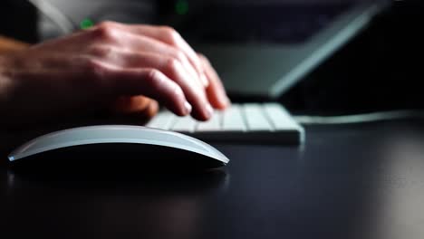 persona usando un mouse en una habitación oscura, escribiendo en el teclado de la computadora - profundidad de campo en cámara lenta