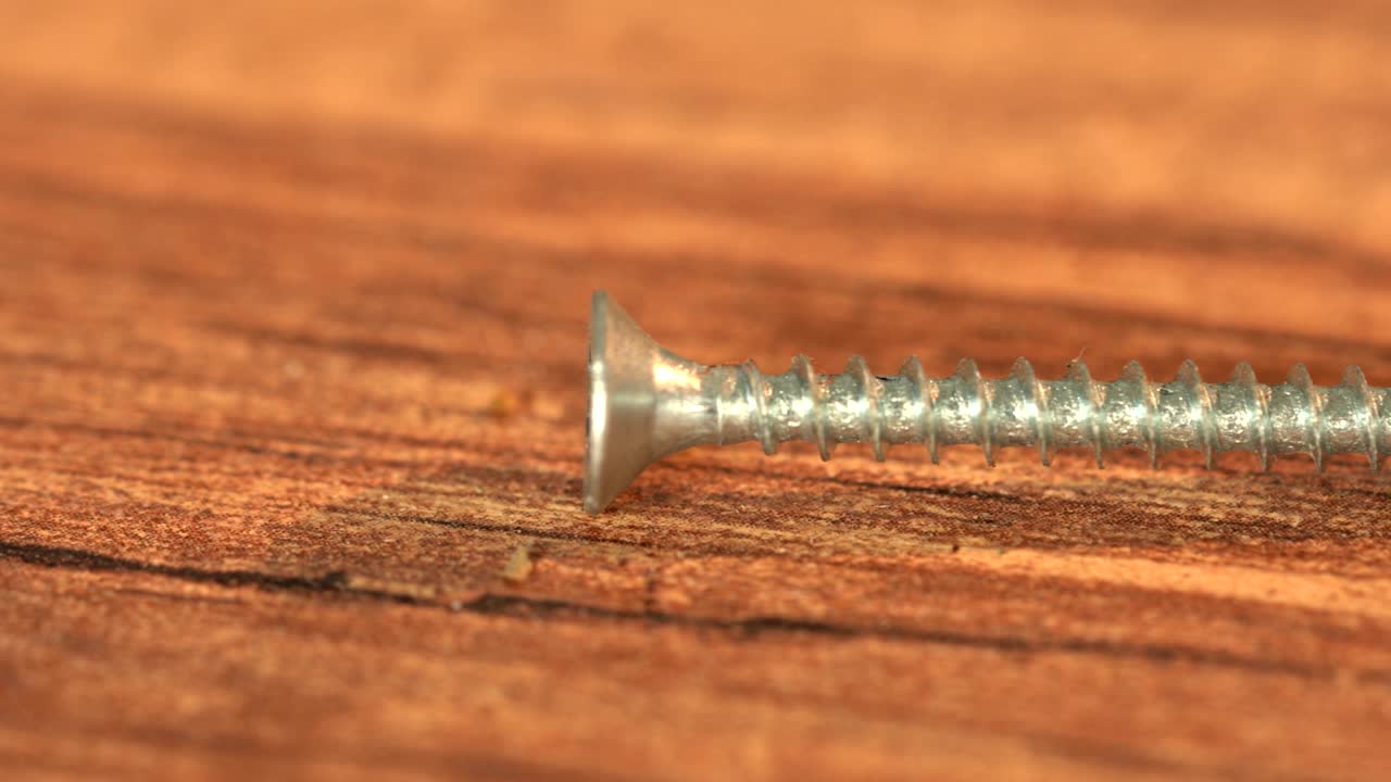 tornillo de acero en una mesa de madera. producción de tornillos, montón de detalles metálicos, primer plano