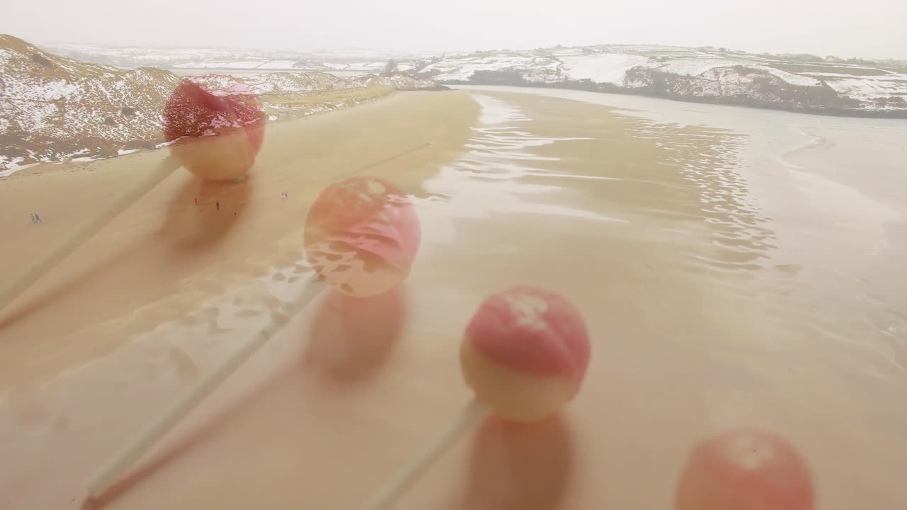 Lollipops with pink and white colors decorating sandy beach near water