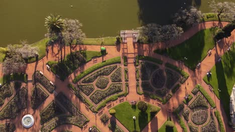 aerial top down shot of green cart driving at rosedal of palermo park of buenos aires near lake during sunny day