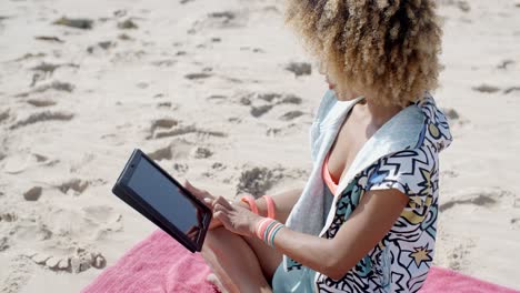mujer usa tableta en la playa