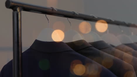 animation of bokeh lights over jackets hanging on display in clothes shop