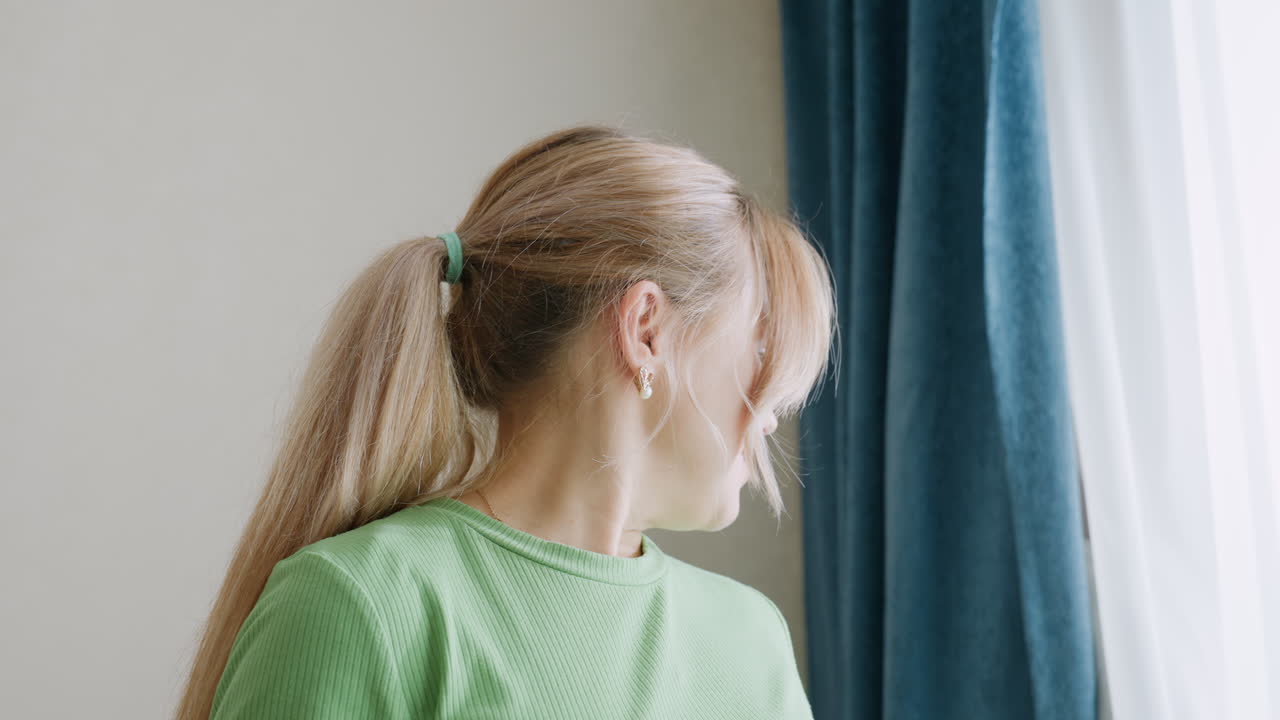 Close up of cheerful mother covering face with both hands while counting aloud during playful family hide and seek activity inside cozy sunlit room with curtains and soft pastel walls