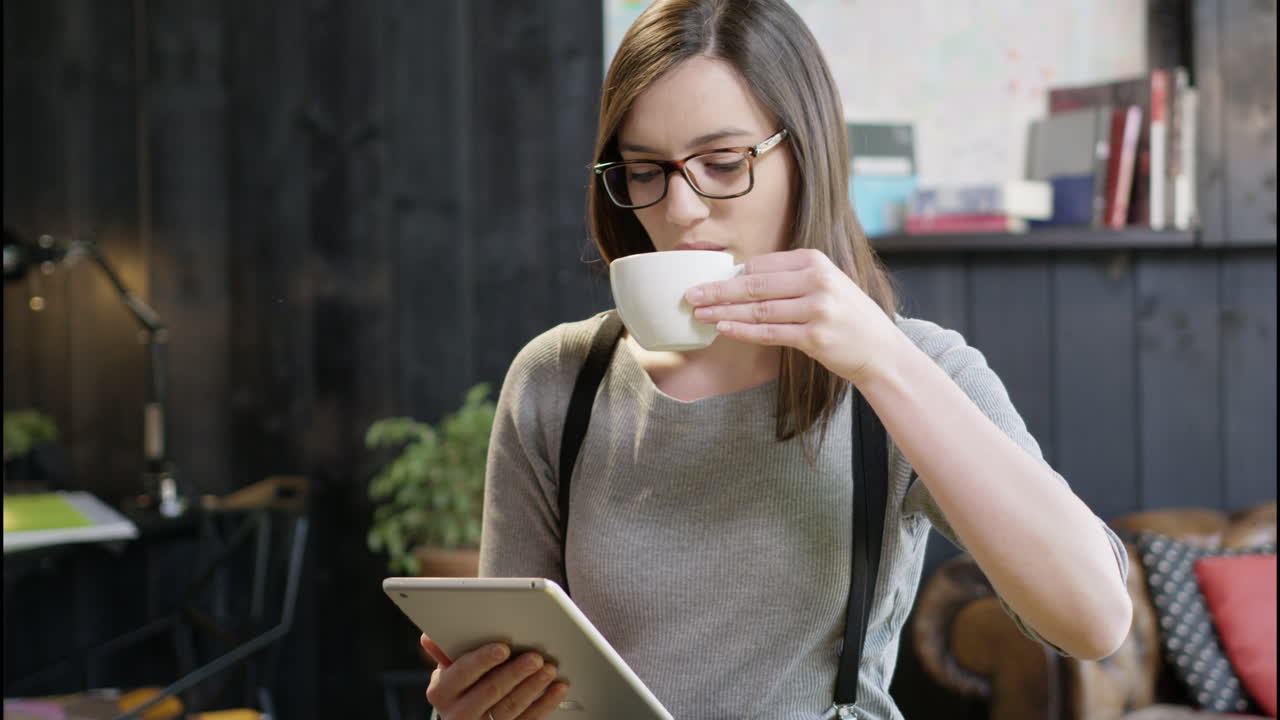 la mujer usa tabletas, bebe café, trabaja.