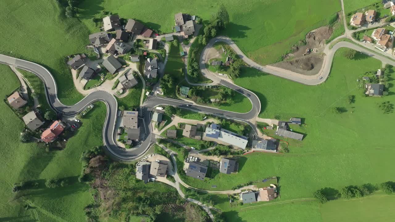 이탈리아의 돌로미트 산맥에 있는 라 발 마을의 휘어지는 도로를 촬영한 공중 영상입니다.