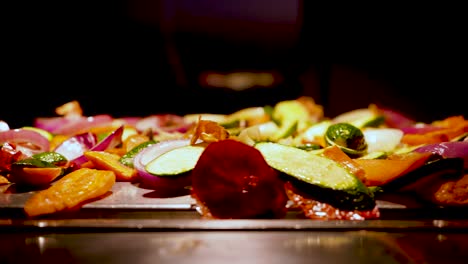 a slow tracking shot of a colorful fried veggie mix on a wooden platter