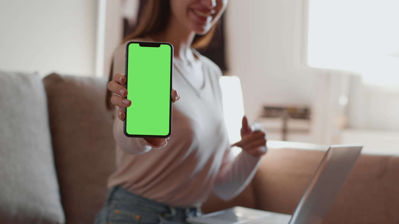 Woman Showing Green Screen Smartphone on Couch