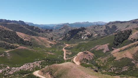 Vista-Aérea-De-Un-Sinuoso-Camino-De-Tierra-A-Través-De-Las-Montañas