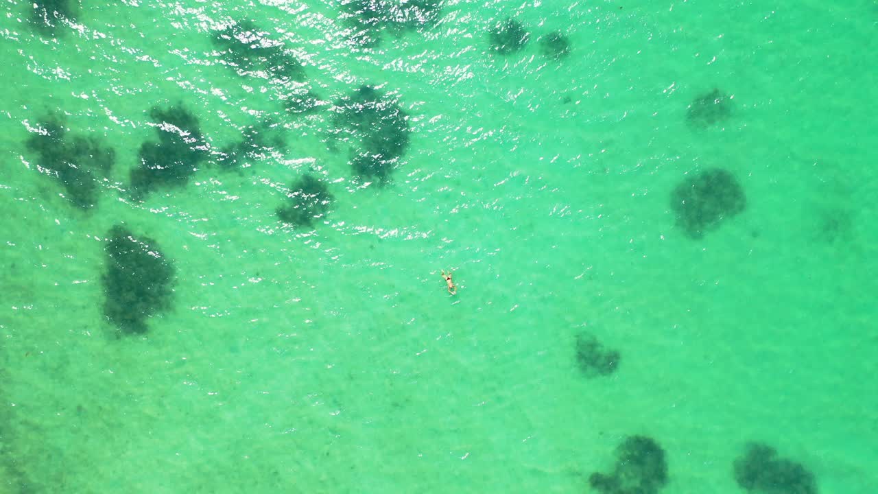 mujer en topless nadando en el agua azul