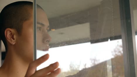 joven de pie cerca de la ventana en casa 4k