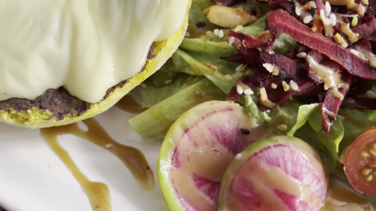 A plated Mexican dish featuring a fresh salad with watermelon radish, crispy meat, sesame seeds, and drizzled dressing