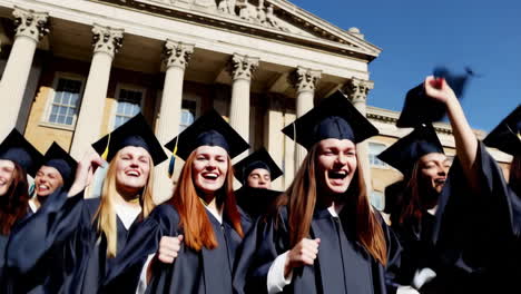 graduates celebrating by throwing caps in the air outside a university building