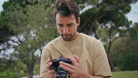 periodista de aspecto serio cámara de fotografía en el parque de cerca. hombre hispano guapo