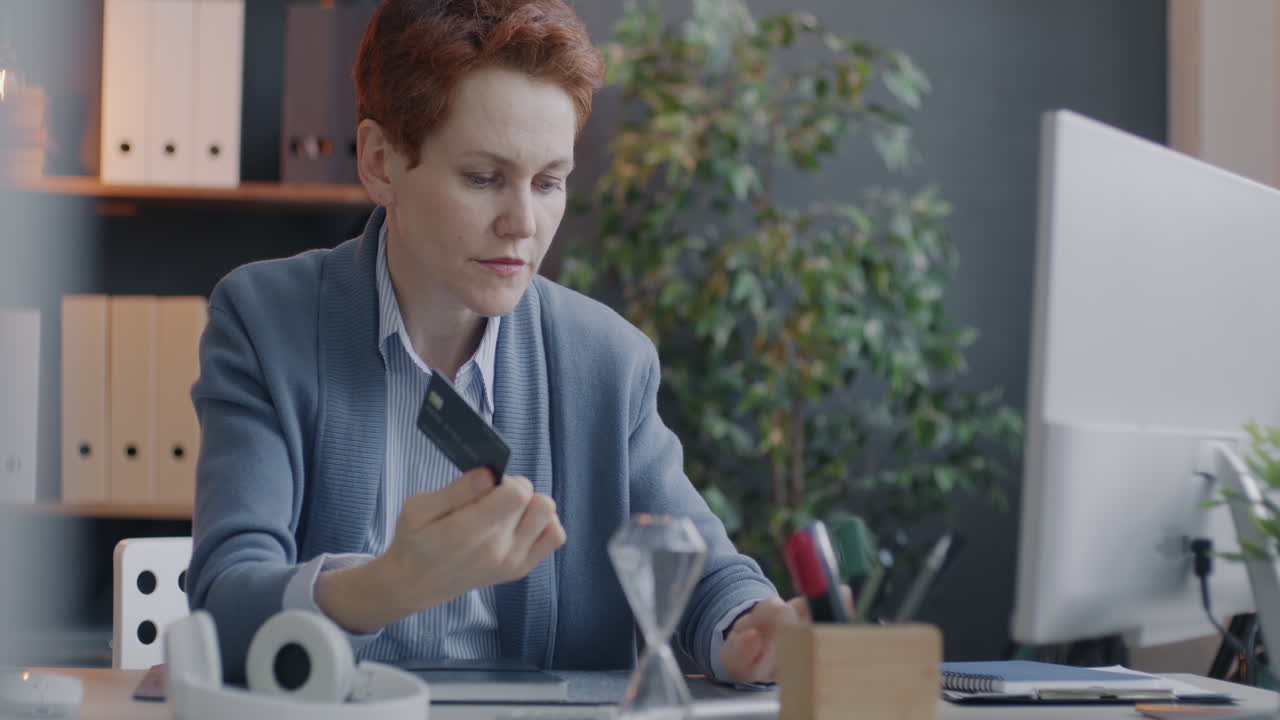 Woman using credit card on computer in office