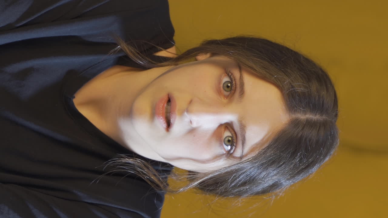 video vertical de una mujer joven mirando a la cámara con ojos cobardes.