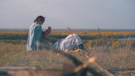 Pareja-De-Lesbianas-Descansa-Sobre-La-Hierba-Y-La-Hoguera-En-Primer-Plano