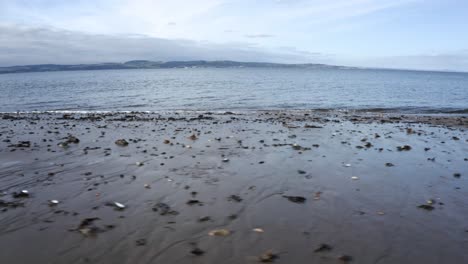 Ruhige-Wellen-An-Einem-Strand-Mit-Blick-über-Das-Wasser-Auf-Eine-Insel-|-Edinburgh,-Schottland-|-4k-Bei-30fps