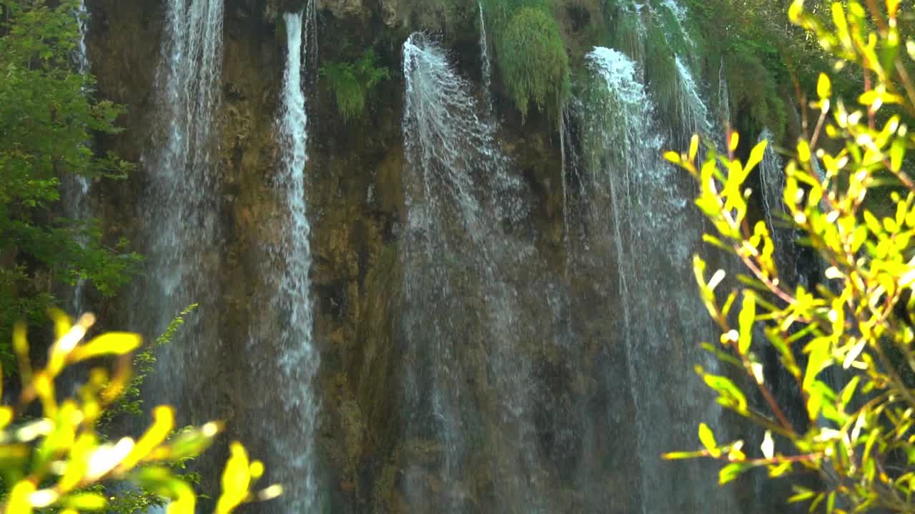 cascadas altas y delgadas con arbustos verdes brillantes en primer plano en el parque nacional de los lagos de plitvice en croacia, europa a ¼ de velocidad