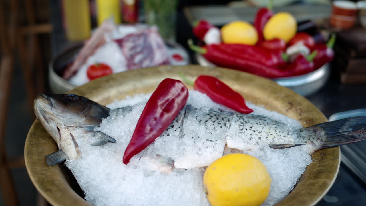 Raw fish on ice with peppers and lemons on a plate, prepared for cooking in a kitchen