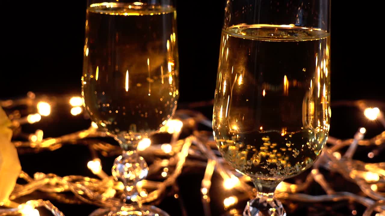 Calici da champagne e una rosa sullo sfondo di ghirlande luminose