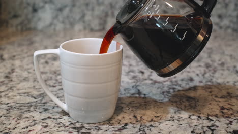 Close-up-shot-showing-hand-pouring-fresh-hot-coffee-in-white-cup,static