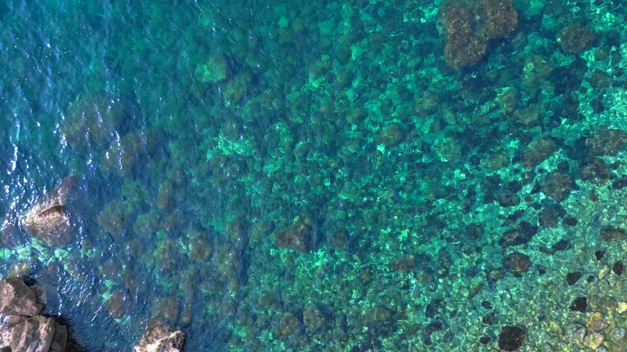 Transparent turquoise water flows between rocks in a bay in Ibiza, Spain. Gorgeous aerial view flight vertical bird's eye view drone