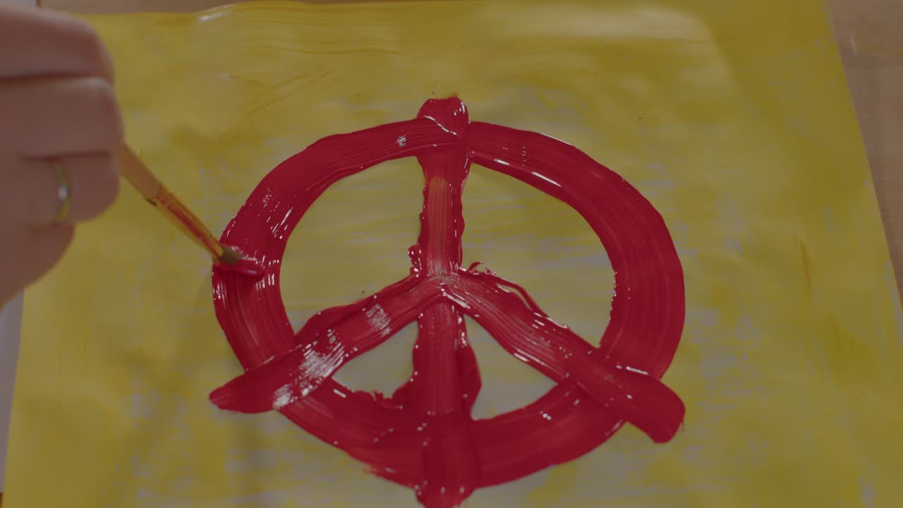 질의 손은 노란색 배경에 태평양의 기호를 그립니다.