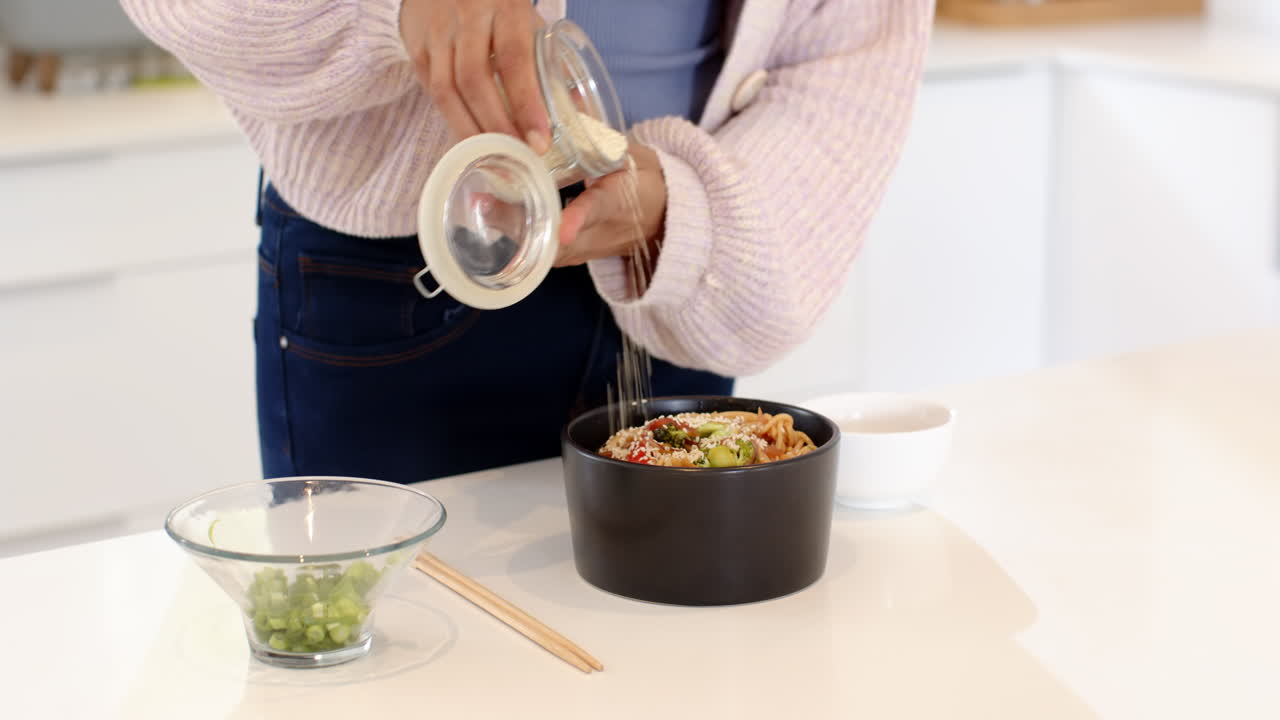 Preparing festive Indian noodle bowl with fresh vegetables and sesame seeds at home