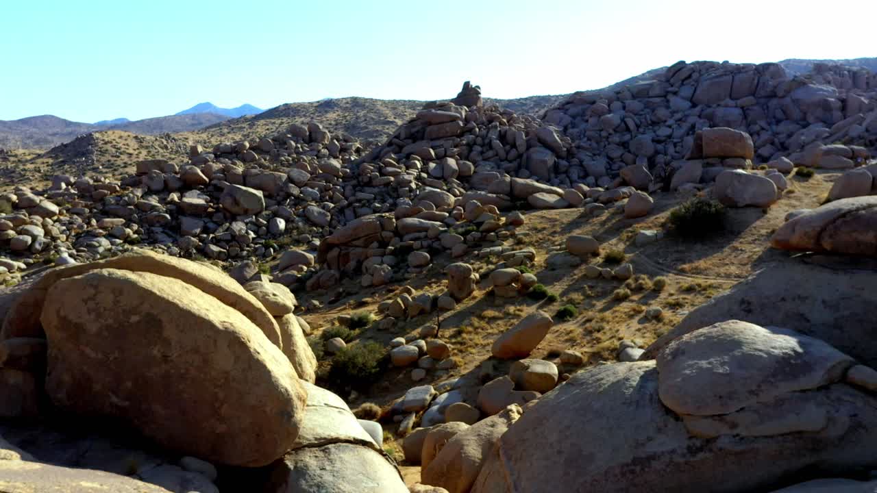 vuela sobre algunas grandes rocas en el desierto del sur de california con un cielo despejado y sin nubes.