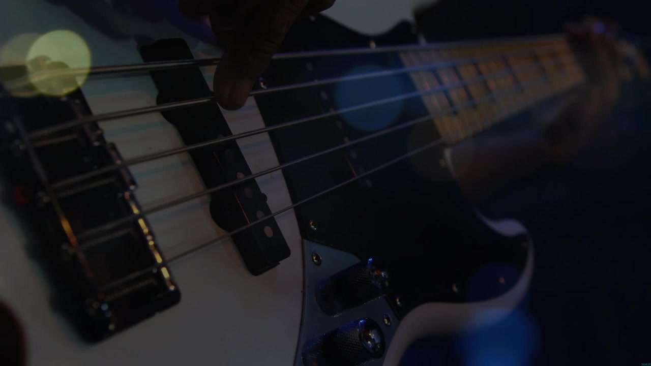 Mano destra che si avvicina ai pickup, iniziando a pizzicare e smorzare le corde del basso, creando un groove musicale.