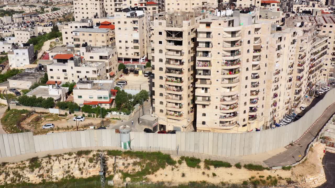 Aerial view of a densely populated urban area featuring a prominent concrete separation barrier