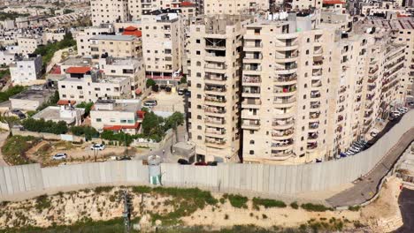aerial view of a densely populated urban area featuring a prominent concrete separation barrier