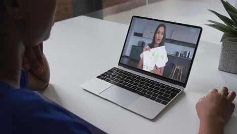 Mid-section-of-african-american-woman-having-a-video-call-on-laptop-with-female-colleague-at-office