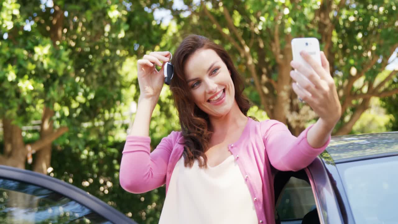 mujer tomando un selfie en el teléfono móvil cerca del coche