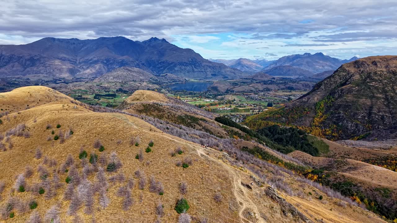 Drone flies over German Hill, Arrowtown, New Zealand, capturing moody clouds, lush hillsides, and scenic Central Otago landscapes on an overcast day