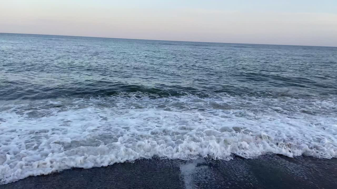 Landscape of a beach on the coast of the Costa del Sol, with calm waves on the shore before a beautiful sunset