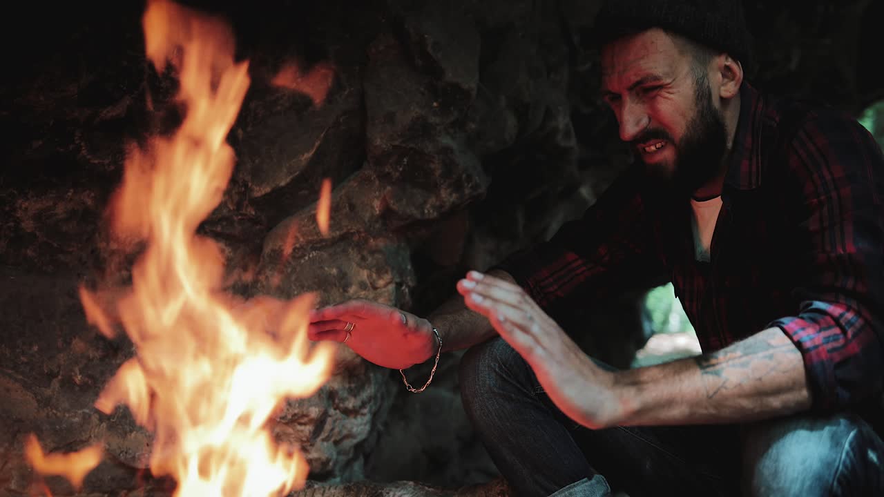 Man warming himself by a campfire in a cave