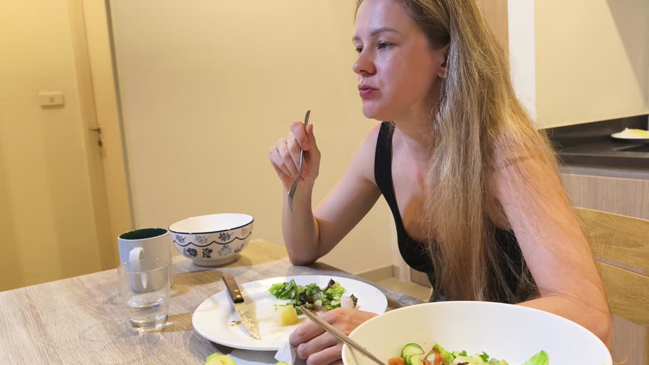 Woman eating healthy salad at the table