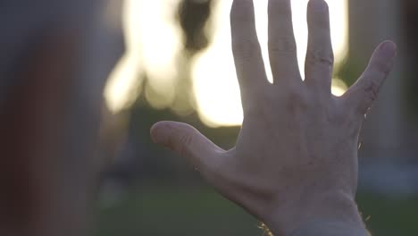 his old hand stretches out his hand against the sun.