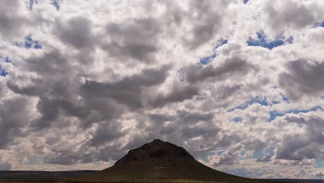 timelapse moody low clouds passing over isolated butte, mojave desert