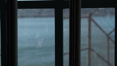 view from inside of alcatraz prison, metal bars on window and barbed wire fence, california usa